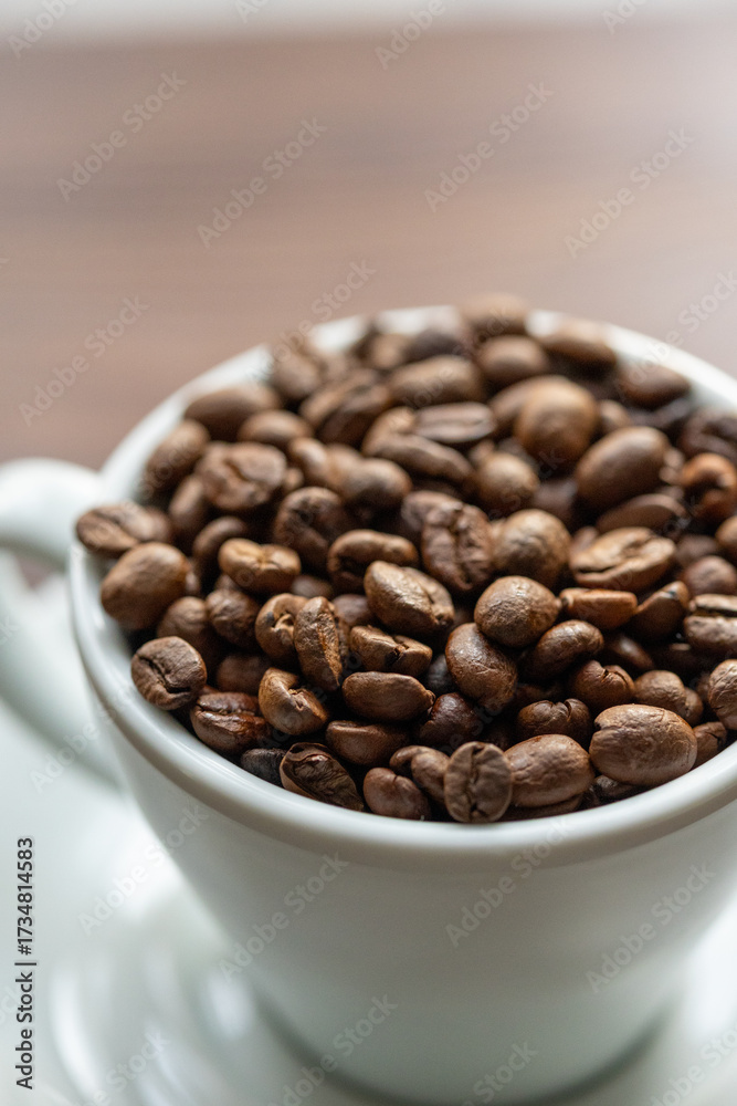 Fototapeta premium Coffee Beans in a Large White Cup on a Brown Table