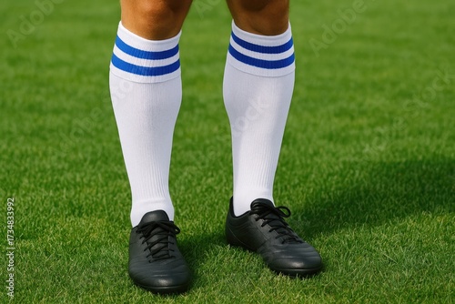 Soccer player wearing black cleats and white socks on green grass  