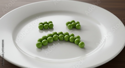 Green peas arranged to form a sad face on white plate
