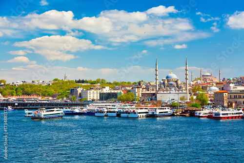 Foto Eminonu district in Istanbul with New Mosque or Valide Sultan Mosque and Hagia Sophia with ferry ships during summer sunny day