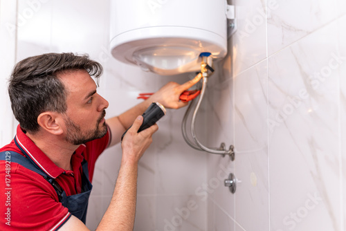 Skilled technician repairing water heater in modern bathroom setting during daylight hours