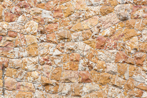 Close-up of natural stone wall with irregular shapes and warm earthy tones. Ideal for backgrounds, design projects, architecture, and construction concepts.