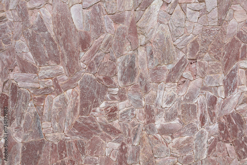 Close-up of pink stone wall with irregular shapes and natural patterns. Ideal for backgrounds, design projects, rustic architecture, and construction concepts.