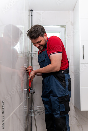 Plumber working on plumbing installation in modern bathroom at home during daylight hours