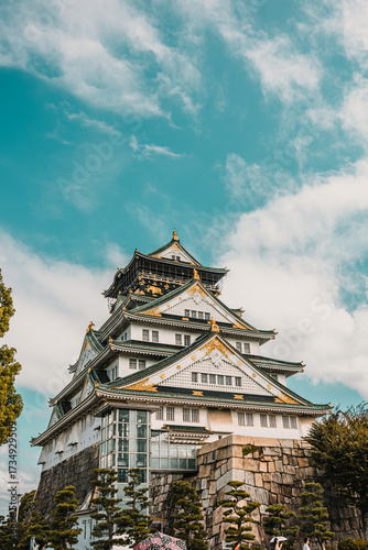 Detailed view of the multi-tiered white and gold Osaka Castle structure, built atop a stone wall.