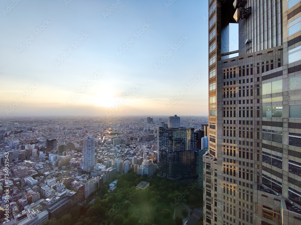 Fototapeta premium 都心の高層ビルから広がる街並みを眺める夕暮れ時のパノラマ写真で右端の建物がフレームのアクセントになっています