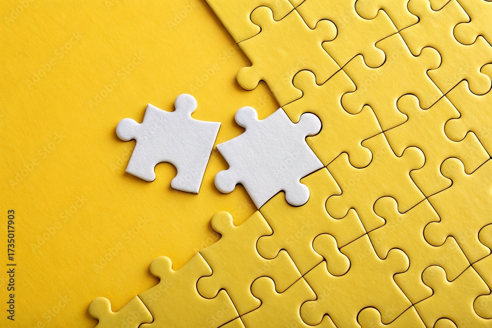 Obraz premium Two white puzzle pieces on a bright yellow background, symbolizing problem-solving and creativity