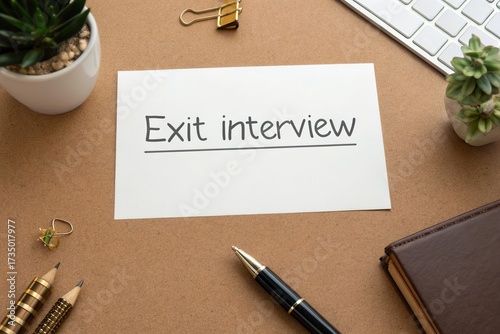 Desk setup featuring an 'Exit interview' note with office supplies and plants, conveying a professional atmosphere