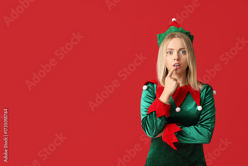 Young woman in elf costume on red background