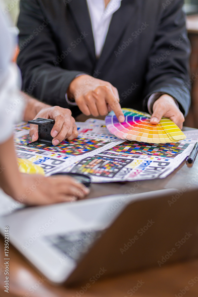 Fototapeta premium Team graphic designer checking print quality of media graphics proof print and color guides in printing industry. Selected focus