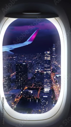View from an airplane window of a sprawling, illuminated city at night, with a magenta-tipped wing