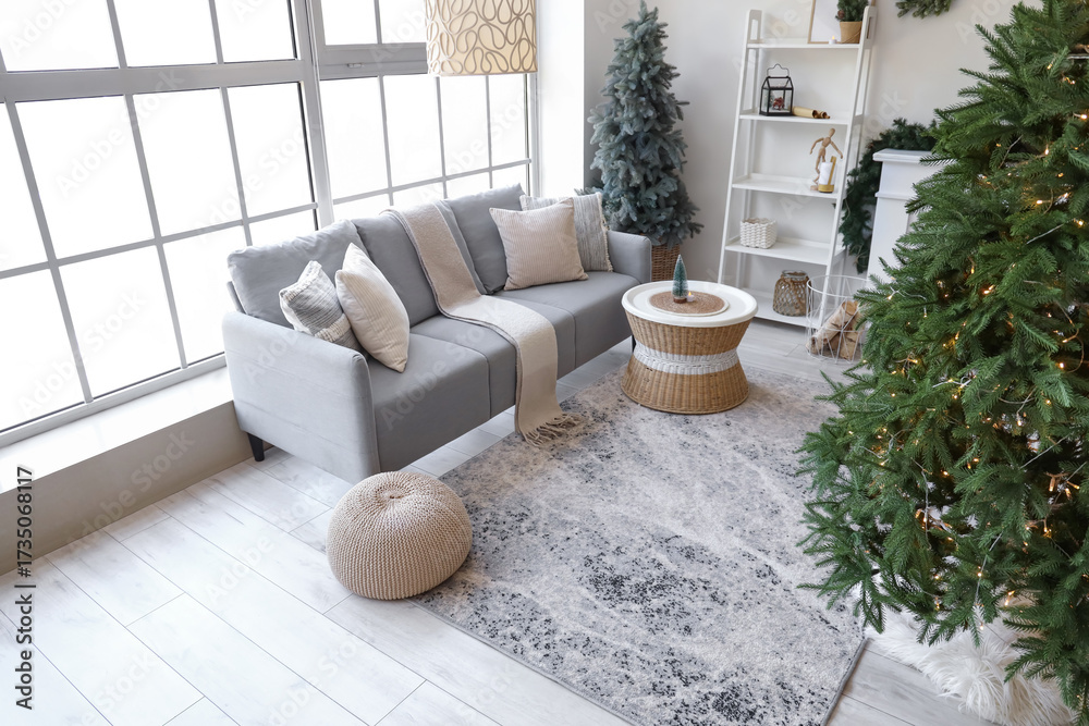 Naklejka premium Interior of living room with grey sofa, Christmas tree and festive decorations