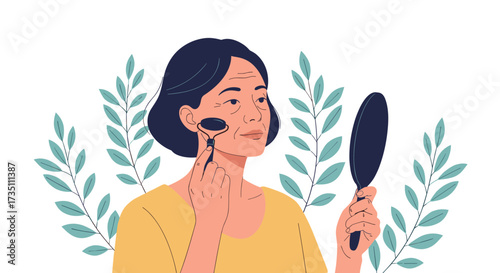 Mature woman using a jade roller on her face while looking in a mirror.