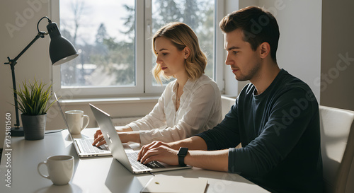 Couple working on laptops at a bright desk