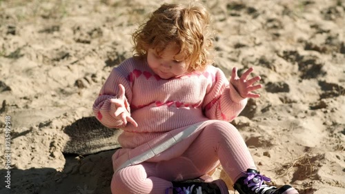 Child playing in sandy area wearing warm sweater on a bright sunny day outdoors