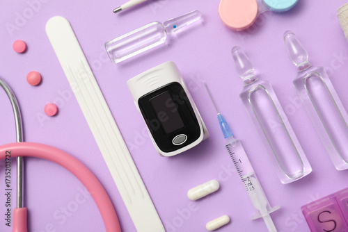 Composition with pulse oximeter, stethoscope and medicines on lilac background, closeup
