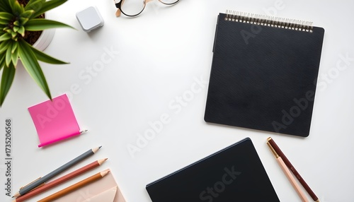 Overhead shot of a white desk with a plant, notepad, glasses, pencils, and sticky notes, suggesting a workspace or creative environment.