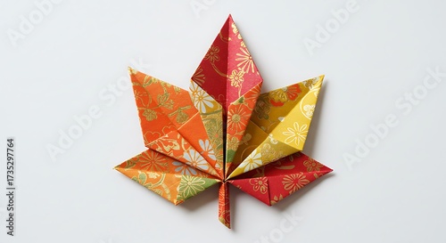 Handcrafted origami maple leaf in warm autumn colors, decorative paper art on white background
