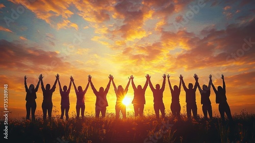 Group of people holding hands and raising arms together at sunset with vibrant colorful sky and sun glowing behind them, symbolizing unity and joy