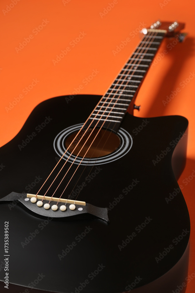Fototapeta premium Modern black guitar on orange background, closeup