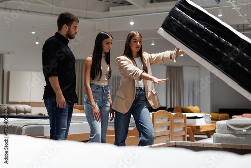 Salesperson showing mattress storage feature to couple