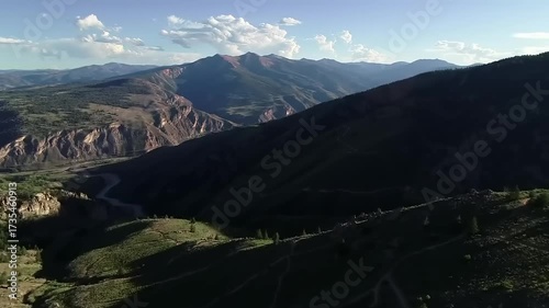 Elevated scenic mountain vista with dynamic lighting casting shadows over a rugged natural landscape during daytime hours