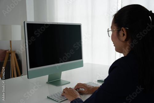 Asian Female Accountant Diligently Working on Desktop Computer. Modern Office Setting for Financial Reporting and Analysis, Highlighting Focus and Professionalism.