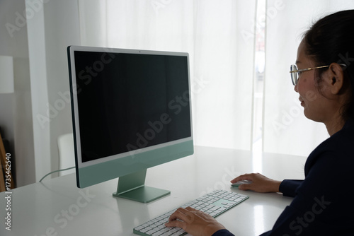 Asian Female Accountant Diligently Working on Desktop Computer. Modern Office Setting for Financial Reporting and Analysis, Highlighting Focus and Professionalism.