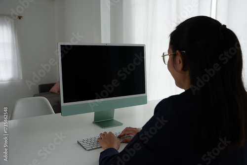 Asian Female Accountant Diligently Working on Desktop Computer. Modern Office Setting for Financial Reporting and Analysis, Highlighting Focus and Professionalism.