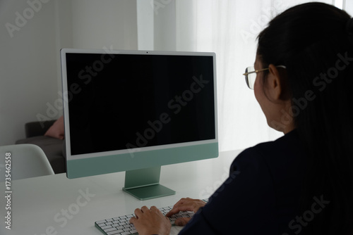 Asian Female Accountant Diligently Working on Desktop Computer. Modern Office Setting for Financial Reporting and Analysis, Highlighting Focus and Professionalism.