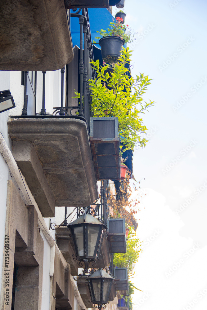 Φωτογραφία Upward view of traditional Mexican balconies with wrought iron railings, classic lanterns, and potted plants, captured on a sunny day in a relaxed, touristic urban setting