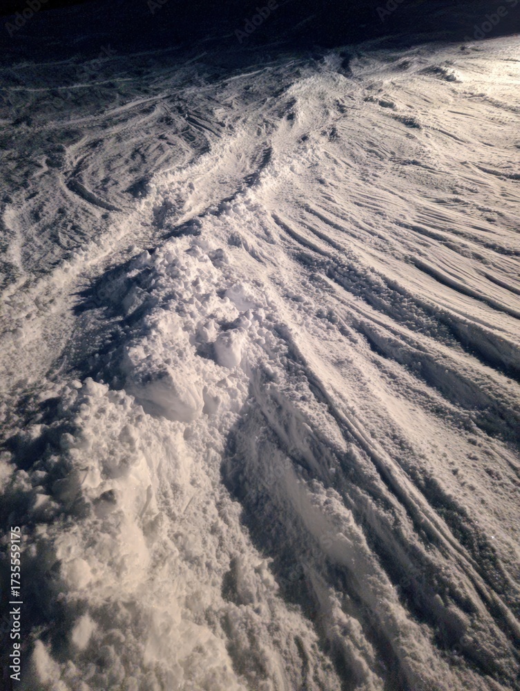 Fototapeta premium Snowy Mountain Terrain with Deep Tracks and Textured Ice Surface in Winter Landscape Under Clear Sky