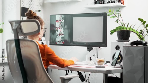 Young female designer working on AI-assisted image generation. She types prompts, monitors creative progress on a computer screen, and combines AI and creativity to enhance her artistic workflow