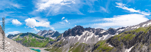 Billede på lærred Panoramic alpine mountain range above the turquoise Lünersee with rugged peaks,