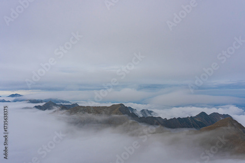 view of highest peaks of romanian carpathian ridge chain from top on very cloudy day with fluffy white clouds at bottom