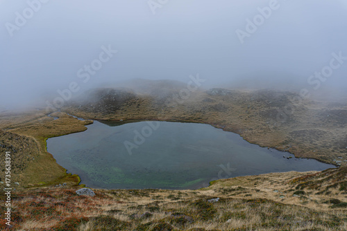 fog in the mountains and glacier lake on autumn moody day 