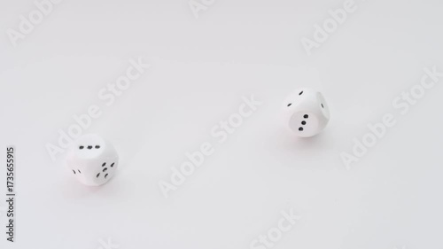 Two dice fall onto a white surface - the number five comes up. Slow motion.