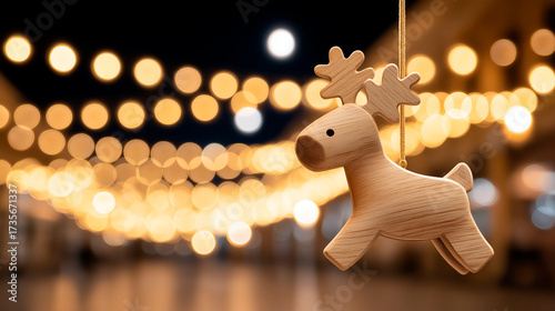 Cute wooden reindeer Christmas ornament hanging in festive outdoor lights with golden bokeh in the background at night