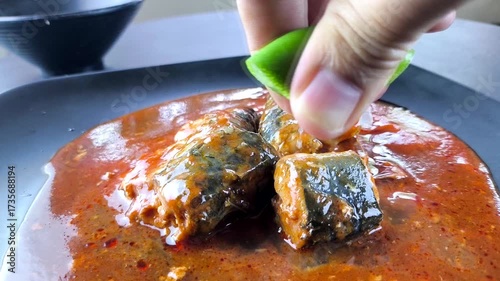 Squeezing a lemon on canned fish in plate, indoor Chiangmai Thailand.