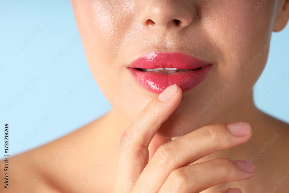 Obraz premium Woman with beautiful pink lipstick on her lips against light blue background, macro view