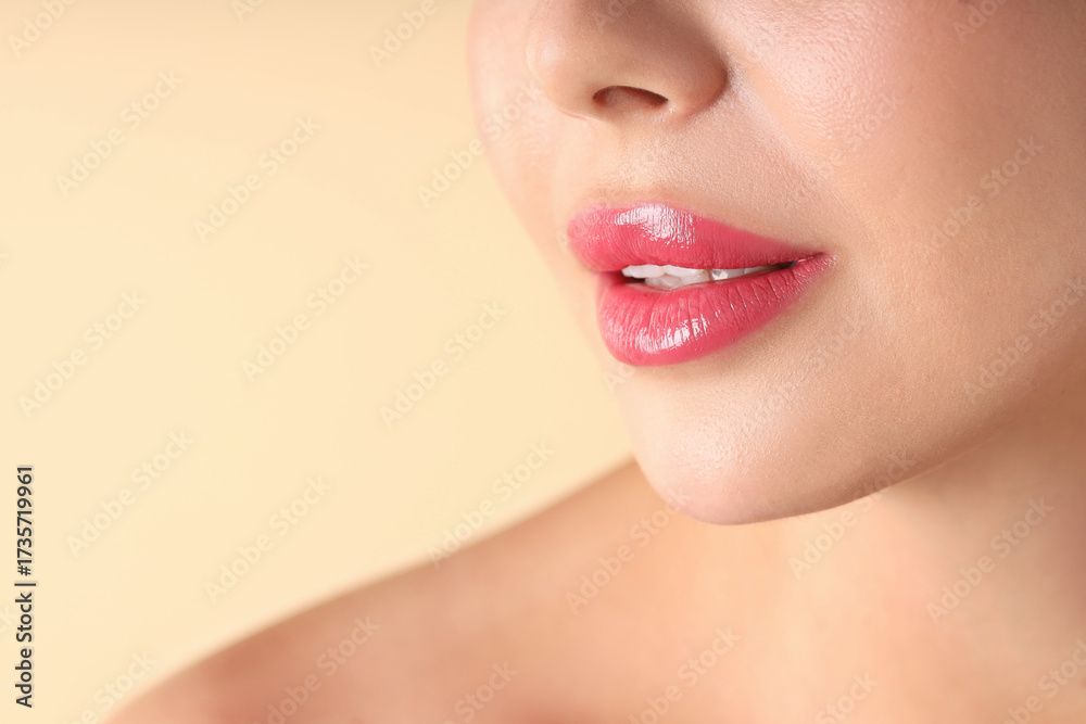 Obraz premium Woman with beautiful pink lipstick on her lips against beige background, macro view. Space for text