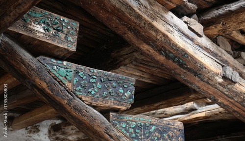 Intricate, aged wooden beams adorned with teal-colored patterns create a textured ceiling design.