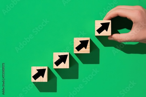 A person's hand building a staircase from wooden cubes with arrows, representing the concept of career development and personal growth