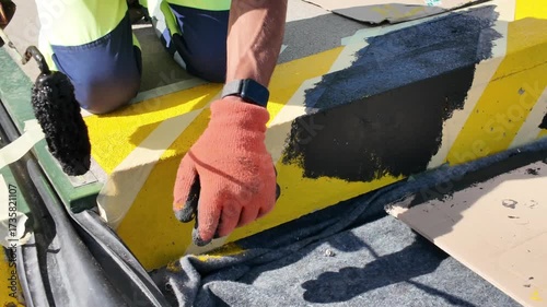 Painting safety stripes on railway platforms. Marking railway platforms with black paint. Concept of color-coded safety marking.