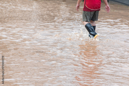 Asian man wears rubber boots or wellingtons walking through the streets during the floods, soft focus, health care concept.