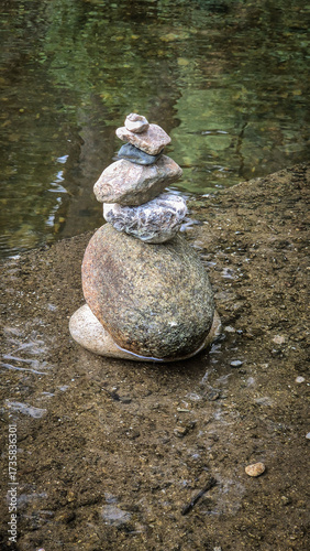 Stacks of balanced river pebbles on the water’s edge symbolize harmony, peace, and focus. Reflective surface and smooth stones evoke zen, mindfulness, and natural art.