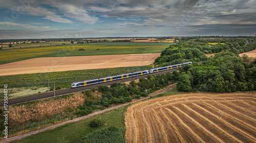 Obraz na plátně Aerial photo of a modern passenger train crossing farmlands