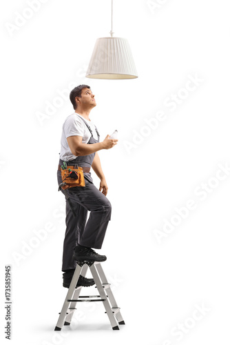 Worker in a uniform on a ladder changing a pendant light bulb