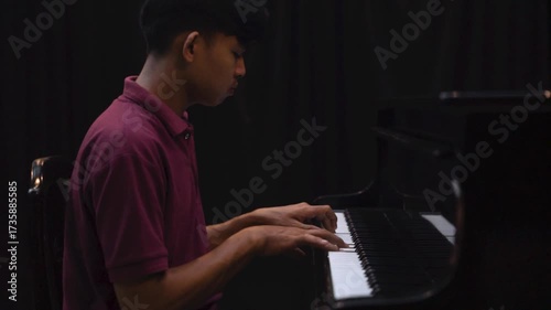 Young Man Playing Grand Piano on Stage Under Dramatic Lighting Music Concert or Recital Scene