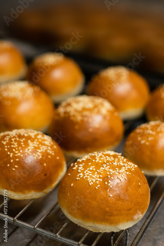 Freshly baked burger buns with sesame seeds cooling on a wire rack